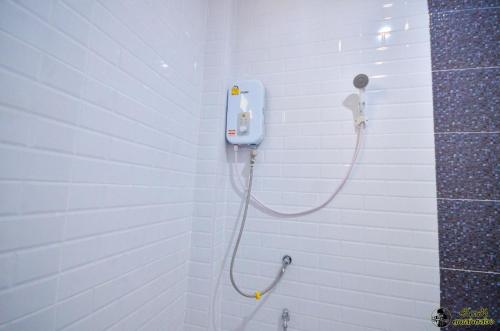 a shower in a white tiled bathroom with a shower at แอ่ว-ดีLD Hotel&Residences in Ngao