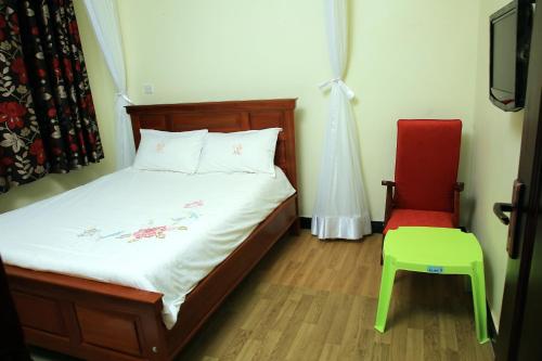 a bedroom with a bed and a red chair at St. Patrick’s Forest House in Entebbe