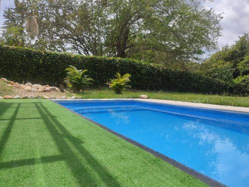 een blauw zwembad in een tuin met groen gras bij Finca de descanso y diversión in Tocaima