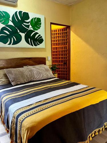 Casa Guiba 1 puerto escondido في بويرتو إسكونديدو: غرفة نوم بسرير مع لوحة على الحائط
