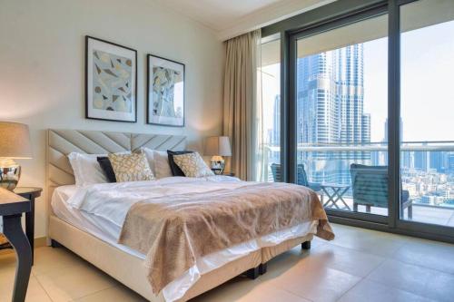 a bedroom with a large bed and a large window at FIRST CLASS 3BR with full BURJ KHALIFA and FOUNTAIN VIEW in Dubai