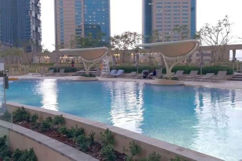 a large swimming pool with chairs and buildings at FIRST CLASS 3BR with full BURJ KHALIFA and FOUNTAIN VIEW in Dubai