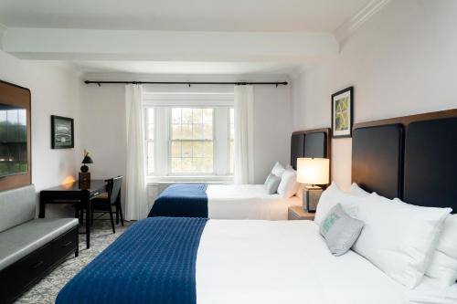 a hotel room with two beds and a desk at Hanover Inn Dartmouth in Hanover