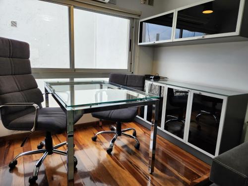 un bureau avec une table en verre et deux chaises dans l'établissement Departamento Alta Gracia, à Alta Gracia