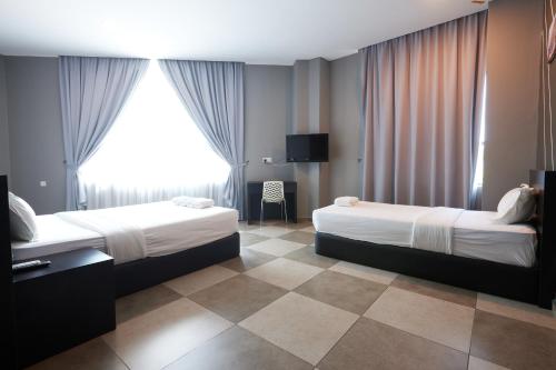 a hotel room with two beds and a tv at Elite Hotel Muar in Muar