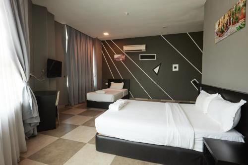 a hotel room with two beds and a chair at Elite Hotel in Muar