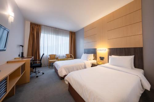 a hotel room with two beds and a television at Ariston Hotel Bangkok in Bangkok
