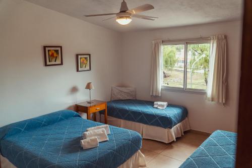 een kamer met 2 blauwe bedden en een raam bij Duplex Madrid in Alta Gracia