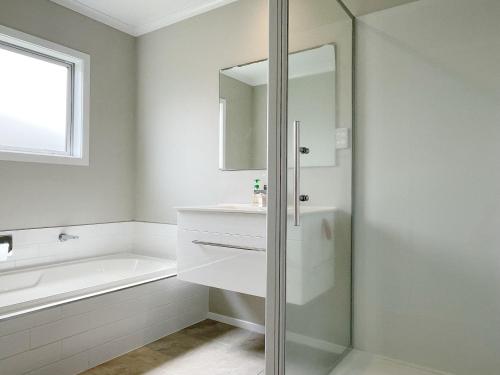 een badkamer met een bad, een wastafel en een spiegel bij Modern and Comfortable Home in Flagstaff in Hamilton