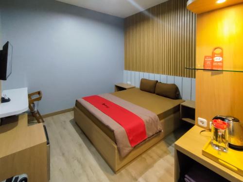 Habitación pequeña con cama y escritorio. en RedDoorz Syariah near Tugu Juang Jambi en Jambi