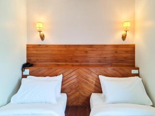 two beds in a room with two lights on the wall at The Peace River Kwai in Ban Tha Makham
