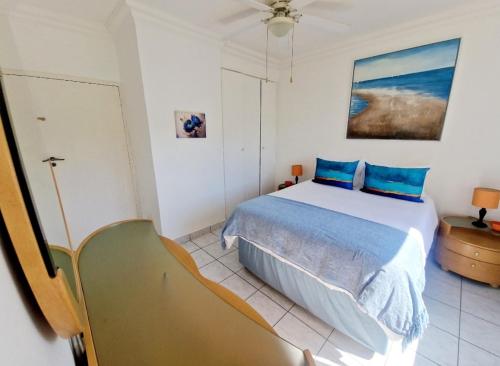 a bedroom with a large bed with blue pillows at Ripple In Time -BBQ - Aircons- 4 Adults 2 kids in Umdloti