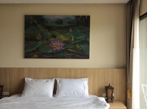a bedroom with a bed with a painting on the wall at Himawari at condominium in Khon Kaen