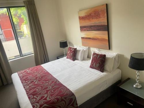 een slaapkamer met een groot bed met rode en witte kussens bij RNR Serviced Apartments Adelaide - Sturt St in Adelaide