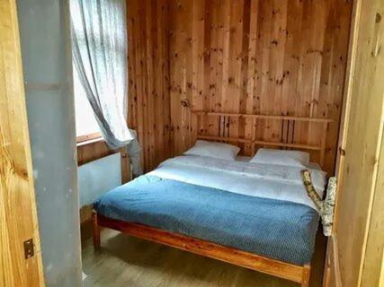 Ce lit se trouve dans une chambre en bois dotée d'une fenêtre. dans l'établissement Casa la montañita, à Quito