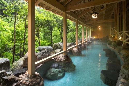 un bâtiment avec une passerelle avec des rochers et des arbres dans l'établissement Yamanaka Onsen Kagari Kisshotei, à Kaga