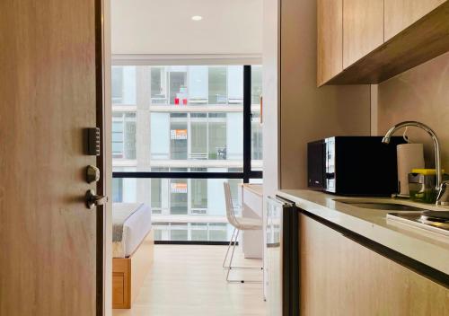a kitchen with a door open to a kitchen with a microwave at Nuo by Wynwood House in Bogotá