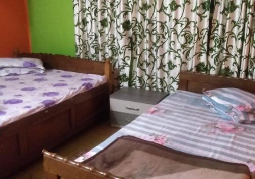 a small bedroom with two beds and a curtain at Karma Homestay by StayApart in Aritar