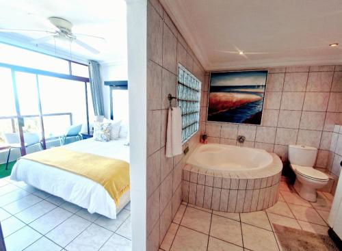 a bedroom with a bed and a tub in a room at Ripple in time - 4 Adults & 2 kids Only in Umdloti