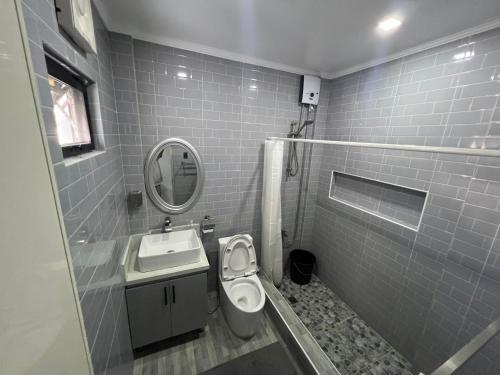 ein Badezimmer mit einem Waschbecken, einem WC und einem Spiegel in der Unterkunft Cozy Haven in Manila