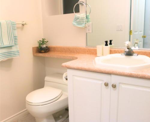 a bathroom with a white toilet and a sink at Lovely 1 bedroom attached full washroom in Surrey