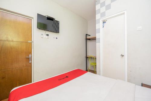 a bedroom with a bed and a television on the wall at RedDoorz @ Darmo Surabaya in Dinojo