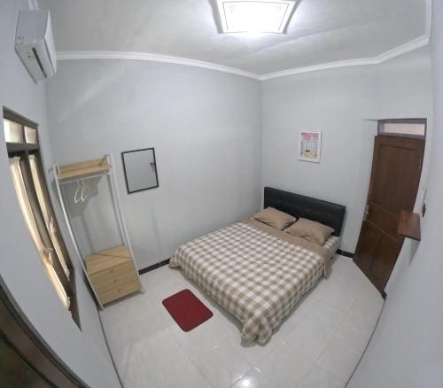 a small bedroom with a bed and a mirror at Griya Rajawali Homestay Jogja in Kejayan