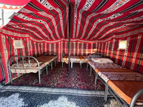 a room with two benches and a red and white striped wall at Big dune camp in Ḩawīyah