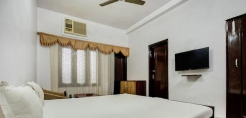 um quarto com uma cama e uma televisão de ecrã plano em Hotel Natraj em Ranchi