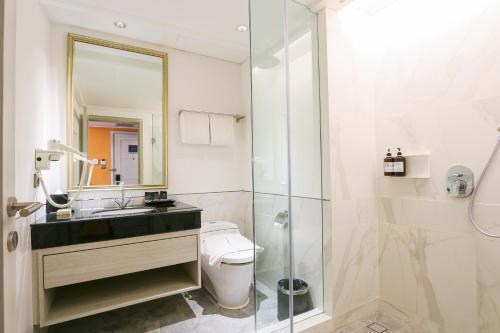 a bathroom with a toilet and a sink and a shower at Java Paragon Hotel & Residences in Surabaya