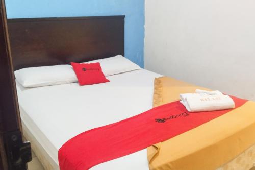 um quarto com uma cama com um cobertor vermelho em RedDoorz near Living Plaza Palembang em Palimbão