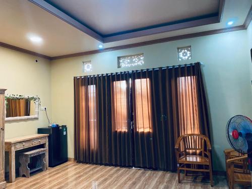 een woonkamer met zwarte gordijnen en een stoel bij Lee Wong House in Ubud