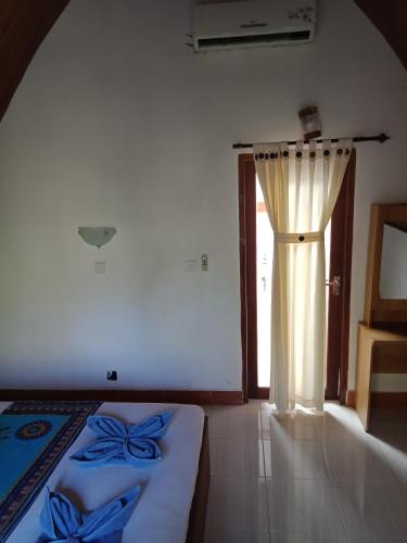 a bedroom with a bed and a door with a curtain at Meno Melani guesthouse in Gili Meno