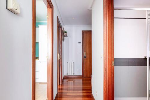 桑圖爾特西的住宿－Exclusivo "Gran Bilbao" Suite Deluxe Top Comfort，一条带白色墙壁和木门的走廊