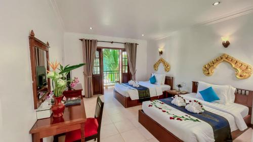 a hotel room with two beds and a table at Villa Indochine d'Angkor in Siem Reap