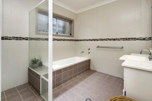 a bathroom with a shower and a tub and a sink at Front Creek 5 - 516 Paragon Ave South West Rocks in South West Rocks