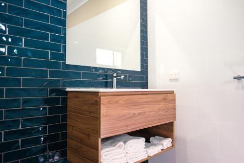 a bathroom with a sink and a mirror and blue tiles at Holbrook Motel in Holbrook