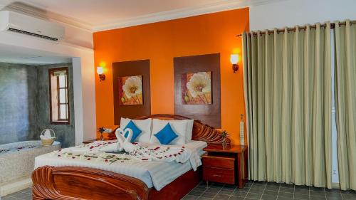 a bedroom with a bed with an orange wall at Villa Indochine d'Angkor in Siem Reap