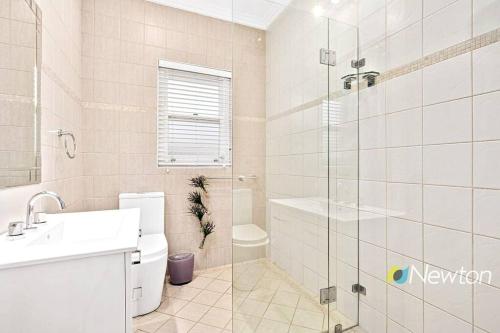 een badkamer met een toilet, een wastafel en een douche bij Sunny Apt on The Esplanade - Aircon in Cronulla