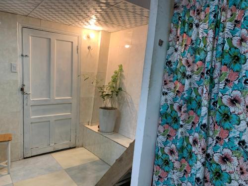 una puerta a una habitación con una cortina de ducha floral en Bồ Công Anh hostel, en Xuan An