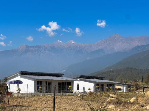 a white house with mountains in the background at Bir Valley Retreat in Bīr