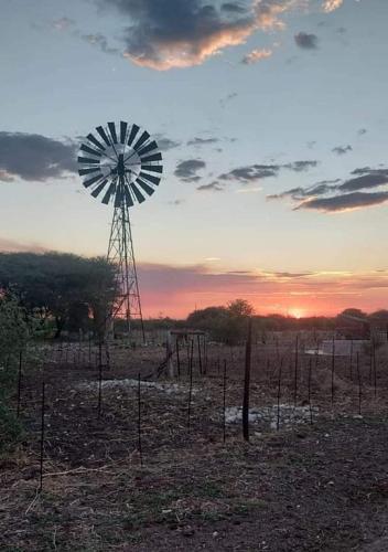 a windmill in the middle of a field with a sunset at Tamboti Farm Self-Catering Accommodation in Tsumeb