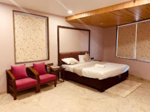 a bedroom with a large bed and two chairs at HOTEL RADHE Anand in Anand