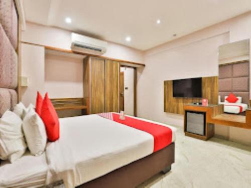 a bedroom with a bed with red pillows and a television at HOTEL RADHE Anand in Anand