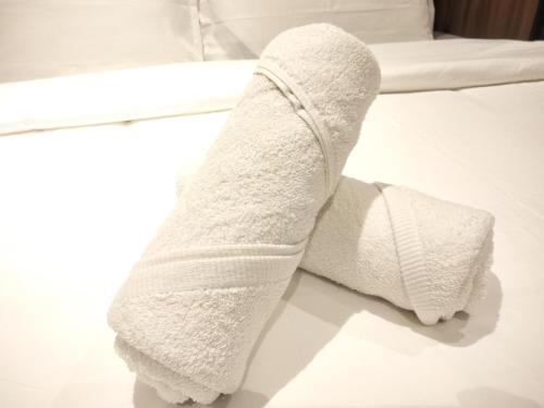 um rolo de toalhas brancas sentado numa cama em Oneiro Quill Residence Klcc em Kuala Lumpur