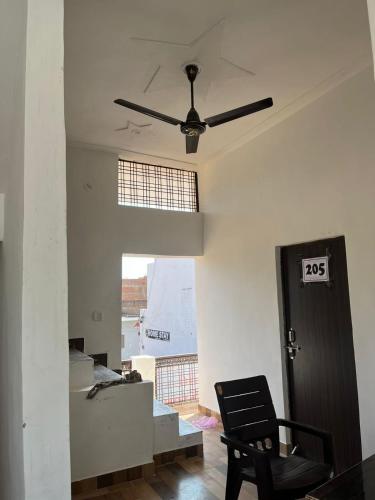 a living room with a ceiling fan and a chair at Indiana home stay in Khajurāho
