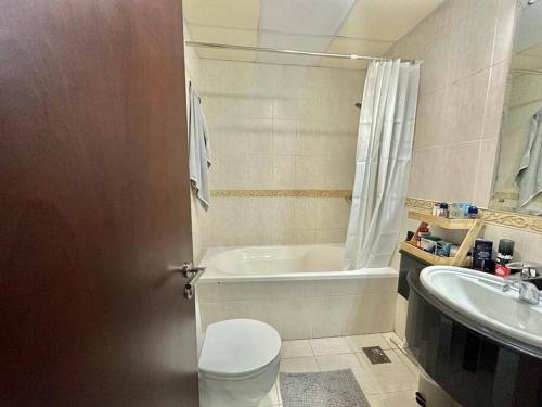 uma casa de banho com uma banheira, um WC e um lavatório. em Stunning 1 BR Apartment in Dubai Marina em Dubai