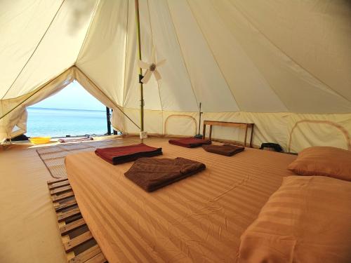 ein Bett in einem Zelt mit zwei Handtüchern darauf in der Unterkunft KAMAKU Bungalows in Koh Rong Sanloem