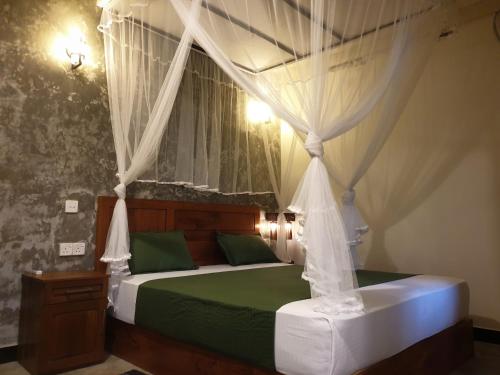 um quarto com uma cama de dossel com lençóis verdes em Rain Forest Star em Deniyaya