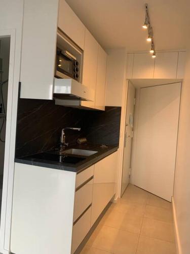 une cuisine avec des placards blancs et un évier ainsi qu'un couloir dans l'établissement Cozy apartment with nice terrace, à Paris